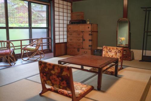 a living room with a table and chairs and windows at Machiya Guest House Carta in Kanazawa
