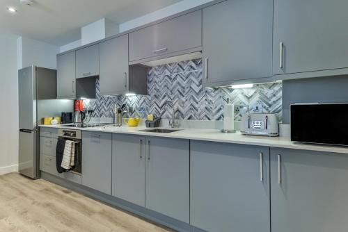a large kitchen with white cabinets and appliances at Finest Retreats - No15 Belle House in Filey