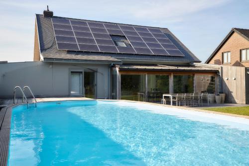 a house with a swimming pool with solar panels on it at Casa Jacaranda in Westvleteren
