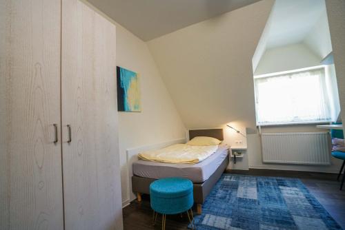 a small bedroom with a bed and a blue stool at Altdeutscher Hof Beckord in Gütersloh