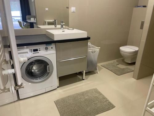 a bathroom with a washing machine and a sink at Yacht Club Apartamenty in Radzyń