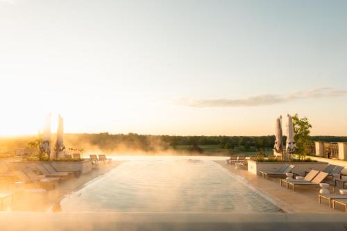 a large swimming pool with chairs and the sun setting at Keswick Hall in Charlottesville