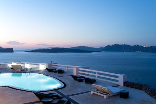 a swimming pool with chairs and a view of the water at Avant Garde Suites in Akrotiri