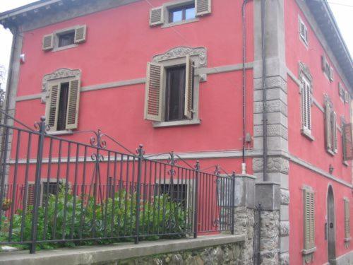 a red building with a fence in front of it at Villa relax montagna di Pistoia in Toscana in Pistoia