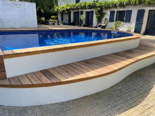 een zwembad met een houten terras en een zwembad bij La Parenthèse in Richebourg