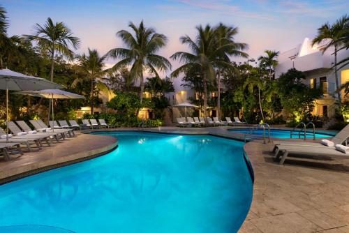 a pool at a resort with chairs and palm trees at Santa Maria Suites Resort in Key West