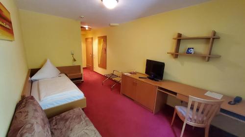 a small room with a bedroom with a desk and a bed at Hotel-Café 3 Kronen in Burglengenfeld