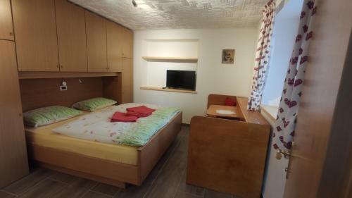 een kleine slaapkamer met een bed en een televisie bij Ciasa Andy in Badia