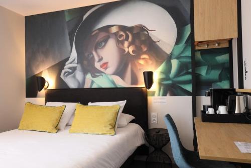 a bedroom with a bed with a painting on the wall at Hôtel la Capelle Millau in Millau