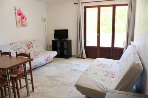 un salon avec un canapé, une table et une fenêtre dans l'établissement HYERES STUDIO 35m² Balcon, à Hyères