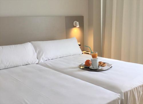 a white bed with a plate of food on it at Hotel El Águila in Utebo