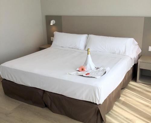 a large white bed with a bottle of champagne on it at Hotel El Águila in Utebo