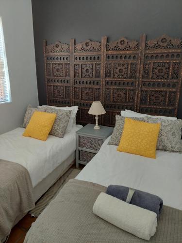 a bedroom with two beds with yellow and blue pillows at Langebaan Sea Cottages in Langebaan