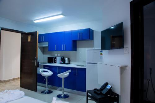 a kitchen with blue cabinets and white appliances at WDC APARTHOTEL - BUEA in Buea