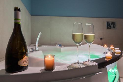 two glasses of wine and a bottle of champagne in a bath tub at Matteotti Luxury Residence in Siracusa