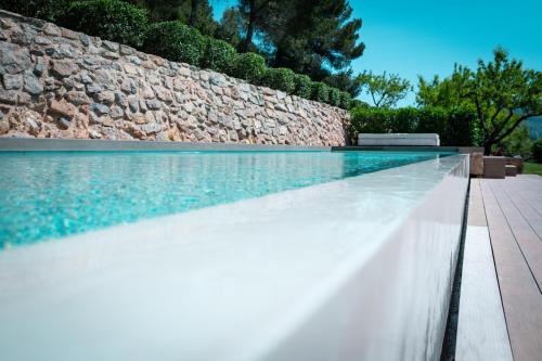 a swimming pool next to a stone wall at Hotel Mas Mariassa in Pratdip