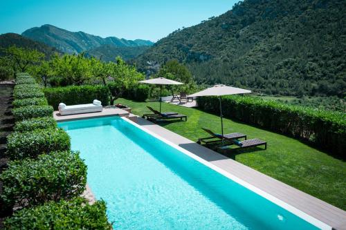 a swimming pool with two chairs and umbrellas at Hotel Mas Mariassa in Pratdip