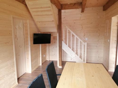 a room with a wooden table with chairs and a television at Chatka pod Krzemienna in Cisna