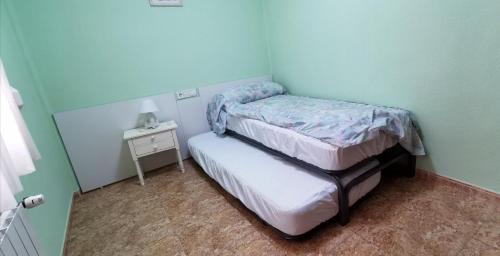 een kleine slaapkamer met 2 bedden en een nachtkastje bij Apartamento Turístico Playa de Peñiscola in Peñíscola