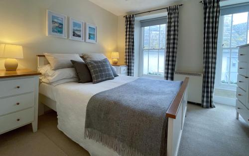 a bedroom with a bed and two windows at Brakestone Cottage in the heart of Port Isaac in Port Isaac