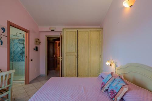 a bedroom with a bed with purple sheets and a closet at Hotel Solanas in Solanas