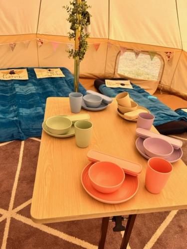 a table with plates and cups on top of a tent at Gwens Garden bell tent in St. Just