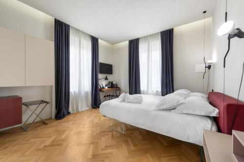 a bedroom with a white bed and a red couch at Villa Fedora Luxury Suites in Lucca