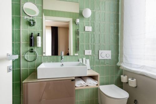 a green tiled bathroom with a sink and a toilet at Villa Fedora Luxury Suites in Lucca