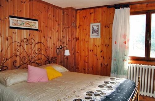 sypialnia z łóżkiem z drewnianymi ścianami i oknem w obiekcie Chalet Gineprino w mieście Vallombrosa