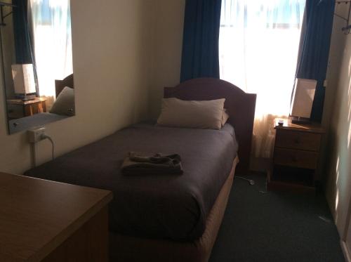 a small bedroom with a bed with a pair of shoes on it at New Whyalla Hotel in Whyalla