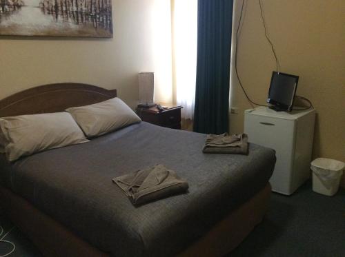 a bedroom with a bed with towels on it at New Whyalla Hotel in Whyalla