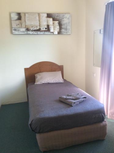 a bedroom with a bed with a wooden head board at New Whyalla Hotel in Whyalla