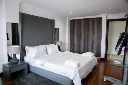 a bedroom with a large white bed with towels on it at WDC APARTHOTEL - BUEA in Buea