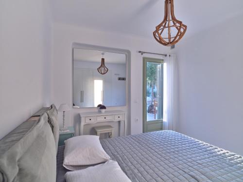 a white bedroom with a bed and a mirror at Marble Villas in Ekatondapilianí
