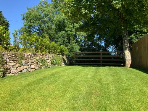 a yard with a stone fence and a tree at Smithaleigh Farm Rooms and Apartments in Plymouth