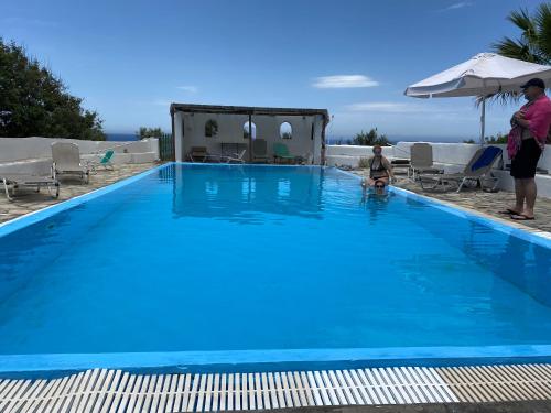 a person standing next to a large blue swimming pool at Siskosplace in Oia