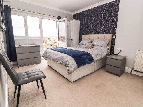 a bedroom with a bed and a chair and a window at Ty Uchaf in Rhyl