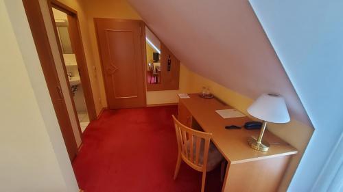 an attic room with a desk and a lamp at Hotel-Café 3 Kronen in Burglengenfeld