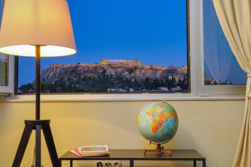 a lamp and a globe on a table in front of a window at Elite Ermou Suites in Athens
