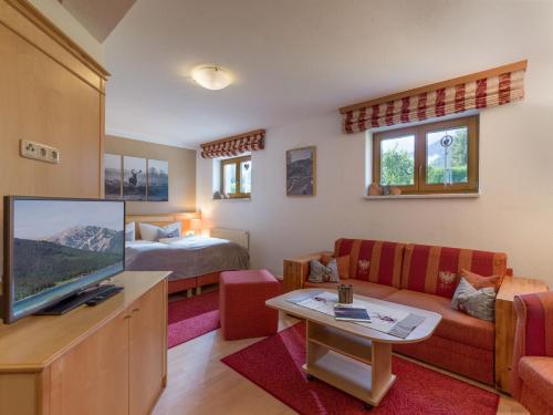 a living room with a tv and a couch and a bed at Ferienwohnung Biechl in Maurach