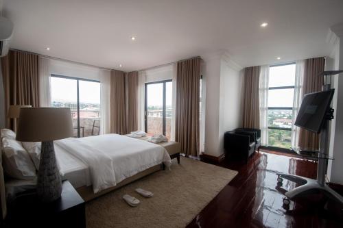 a bedroom with a bed and a tv and windows at WDC APARTHOTEL - BUEA in Buea
