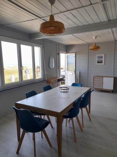 Maison les pieds dans la mer في Quinéville: غرفة طعام مع طاولة خشبية وكراسي زرقاء