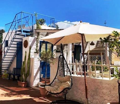 a swing with an umbrella in front of a house at Case Vacanze Levante in Vulcano