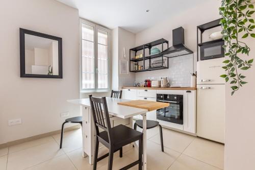 une cuisine avec une table, des chaises et un réfrigérateur dans l'établissement Charmant Appartement en Hypercentre, à Toulouse