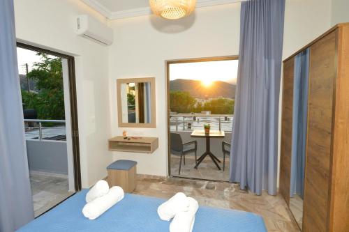 a room with two beds and a balcony with a table at Blue Horizon Kisamos Deluxe Apartment in Kissamos