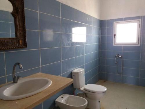 a blue tiled bathroom with a toilet and a sink at Villa en el campo sobre el mar in Ras El Ma