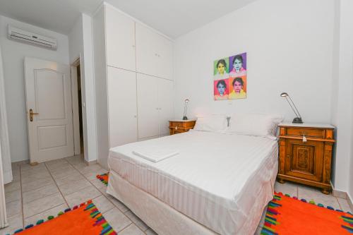 a bedroom with a large white bed and a wooden cabinet at Alento Apartments in Tinos Town