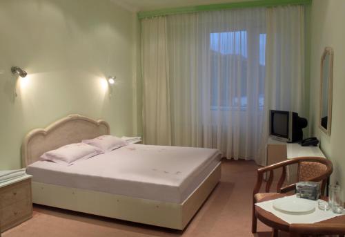 1 dormitorio con cama, mesa y TV en Jermuk Ararat Health SPA, en Jermuk