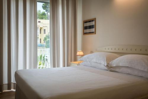 a bedroom with a white bed with a window at Murè Hotel Numana in Numana
