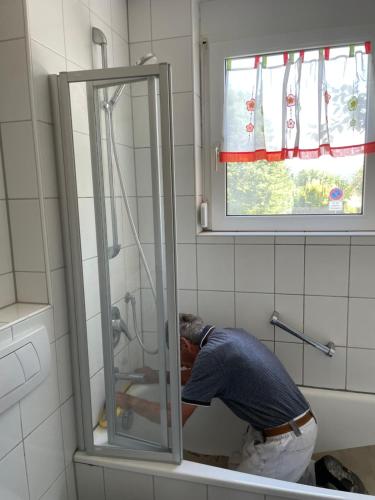 um homem está num chuveiro na casa de banho em Private Wohnung Bunter Hund em Aalen